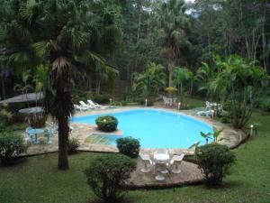 a large swimming pool with chairs and tables in a yard at Spa e Hotel Fazenda Gaura Mandir in Teresópolis