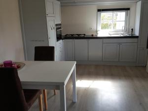 uma cozinha com uma mesa branca e uma janela em De Weide Blick em Biggekerke