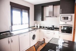 a kitchen with white cabinets and a sink and a table at Apartamento el Palomar in Ayllón