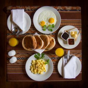 una mesa con platos de desayuno. en Apu Lodge, en Ollantaytambo