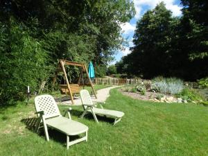 dos sillas y un columpio en un patio en Chalets du pontot, en Le Fay