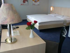 ein Hotelzimmer mit einem Bett und einem Tisch mit einer Lampe in der Unterkunft Hotel Meran Hallenbad & Sauna in Saarbrücken