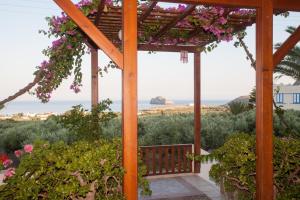 a wooden pergola with pink flowers on it at Liviko View in Xerokampos