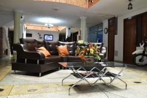 Hotel El Principe في Ocaña: غرفة معيشة مع أريكة جلدية وطاولة زجاجية
