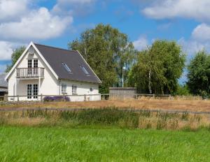 a white house with a black roof in a field at Pedersminde Guesthouse in Fredensborg