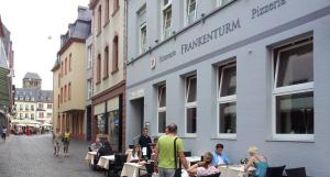 un groupe de personnes assis à des tables à l'extérieur d'un bâtiment dans l'établissement Hotel Restaurant Frankenturm, à Trèves