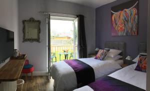 a bedroom with two beds and a table and a window at Angel Cottage in Drymen +18 photos