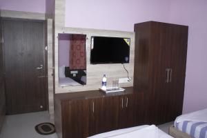 a bedroom with a tv and a cabinet with a mirror at Jeyam Residency in Dindigul