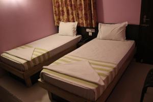 2 camas en una habitación pequeña con paredes rosas en Jeyam Residency, en Dindigul