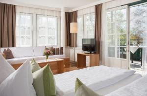 a hotel room with two beds and a television at Hotel Brandauers Villen Superior in Strobl