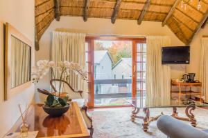 sala de estar con mesa de cristal y ventana grande en Thatchfoord Lodge, en Johannesburgo