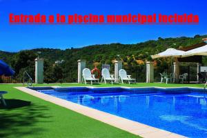uma piscina com cadeiras e um guarda-sol num quintal em Casa Rural Fuente Caraila em Júzcar