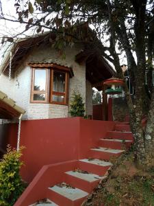 a house with a red fence and a tree at Pousada Canto do Sabiá in Monte Verde