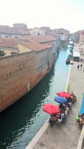 a group of tables with umbrellas next to a river at Appartamenti Paradiso in Venice
