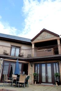 a patio with chairs and an umbrella on a house at Backbrae House Luxury B&B in Lanark