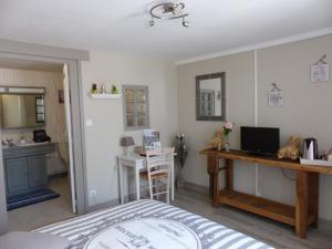 a bedroom with a bed and a desk and a kitchen at La Maison aux Hortensias in Verneuil-en-Bourbonnais