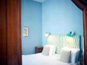 a bedroom with blue walls and a bed with white pillows at Embankment Hotel in Bedford
