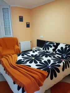 ベガデオにあるApartamento Ria del Eoのベッドルーム(黒と白のベッド、オレンジの椅子付)