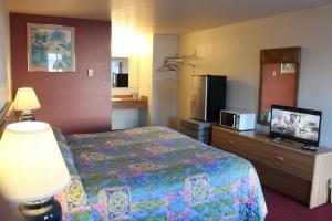 a hotel room with a bed and a flat screen tv at Silver Sands Motel in Florence