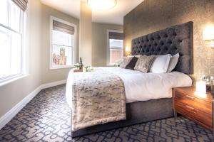 a bedroom with a large bed and two windows at Shipquay Boutique Hotel in Derry Londonderry