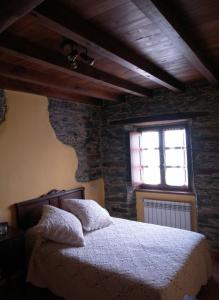 a bedroom with a bed and a brick wall at Apartamentos Rurales El Foro in Andés