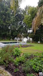 a swimming pool with two white chairs in a park at Afrika-Pearl in Paarl