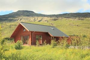 a log cabin with a mountain in the background at Geysir - Modern Log Cabin in Reykholt