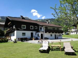 a black and white building with benches in the grass at Ferienwohnung Wetterstein in Lermoos