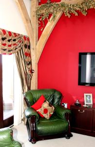 Backbrae House Luxury B&B في لانارك: كرسي جلدي أخضر في غرفة بجدار احمر