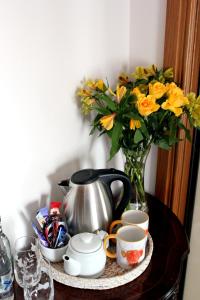 a table with a vase of yellow flowers and cups at Backbrae House Luxury B&B in Lanark