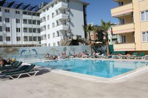 a large swimming pool with lounge chairs and a building at Grand Horizon Apart Hotel in Alanya