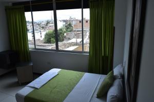 a bedroom with a bed and a window with green curtains at Hotel El Principe Sede Campestre in Ocaña