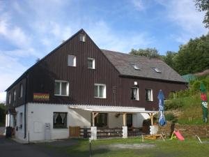 a large brown and white building with a porch at Penzion Hraničář in Loučná pod Klínovcem