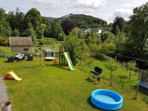 un patio trasero con un parque infantil con un juego de juegos en Au bord de l'eau, en Trois-Ponts