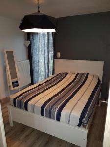 1 dormitorio con 1 cama con edredón a rayas y ventana en Au bord de l'eau, en Trois-Ponts