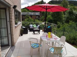 patio con tavolo, sedie e ombrellone di Au bord de l'eau a Trois-Ponts