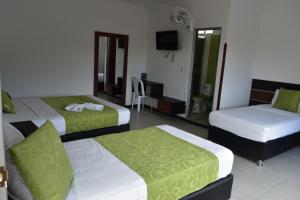 a hotel room with three beds and a television at Hotel El Principe Sede Campestre in Ocaña