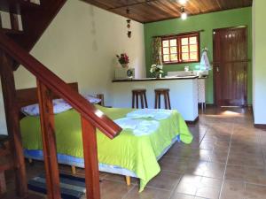 a bedroom with a green bed and a kitchen at Chalé Recanto do Sossego in Gonçalves