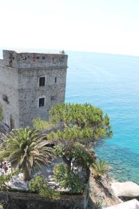 an old building next to the ocean with palm trees at Marianna Quiet Rooms in Monterosso al Mare