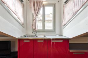 トリノにあるFrancesco da Paola 10の赤いキャビネットと窓付きのキッチン