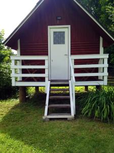 un granero rojo con una puerta blanca y escaleras en Little Garden House, en Kassari