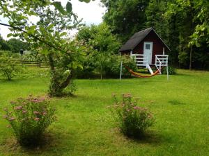 Kassari的住宿－Little Garden House，一座红色的小房子,在田野里设有吊床