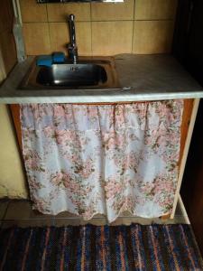 a kitchen counter with a sink with a curtain on it at Little Garden House in Kassari