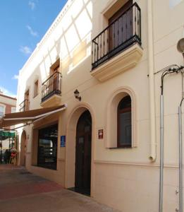 biały budynek z 2 balkonami na ulicy w obiekcie Hostal el Puente w mieście Tabernas