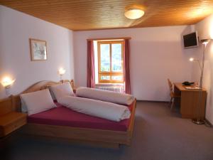 Schlafzimmer mit einem Bett, einem Fenster und einem Schreibtisch in der Unterkunft Hotel Preda Kulm in Bergün