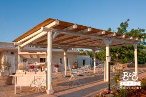 een houten pergola met tafels en stoelen op een patio bij Borgo Mincuccio in Ostuni