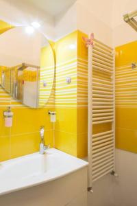 Baño amarillo con lavabo y espejo en Casa Dani&Swing Bed&Books, en Turín