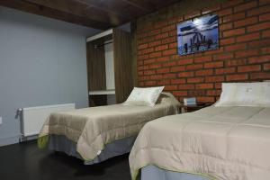 um quarto com 2 camas e uma parede de tijolos em Maromava Patagonia em Puerto Natales