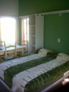 1 dormitorio con 1 cama grande en una pared verde en Complejo Cabañas Cerro Redondo en Tandil