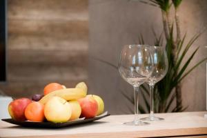 un piatto di frutta su un tavolo accanto a due bicchieri da vino di Prestigious Main Square Apartment a Cracovia
